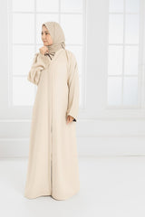 woman standing near window wearing light colour abaya and hijab