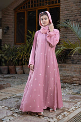 Woman in elegant pink dress posing outdoors in garden setting