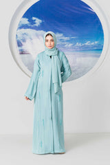 Woman in stylish light blue abaya with ocean background