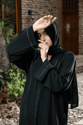 Woman wearing a black abaya with delicate embroidery