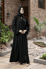 woman wearing black abaya standing in an area surrounded by plants