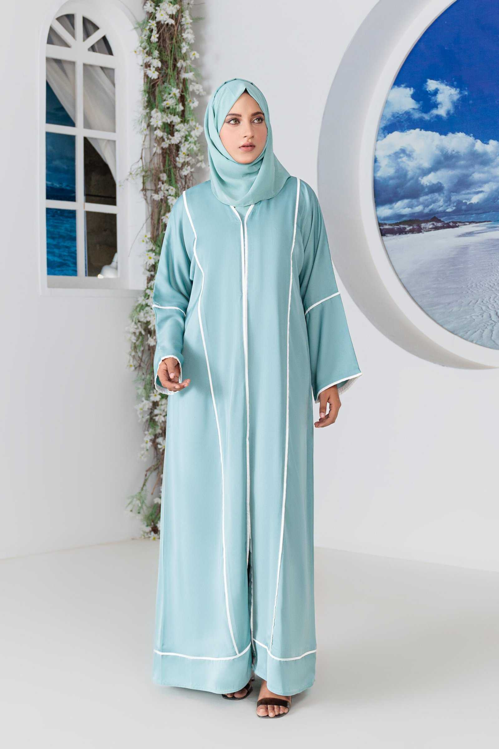 Woman wearing elegant teal abaya in stylish indoor setting