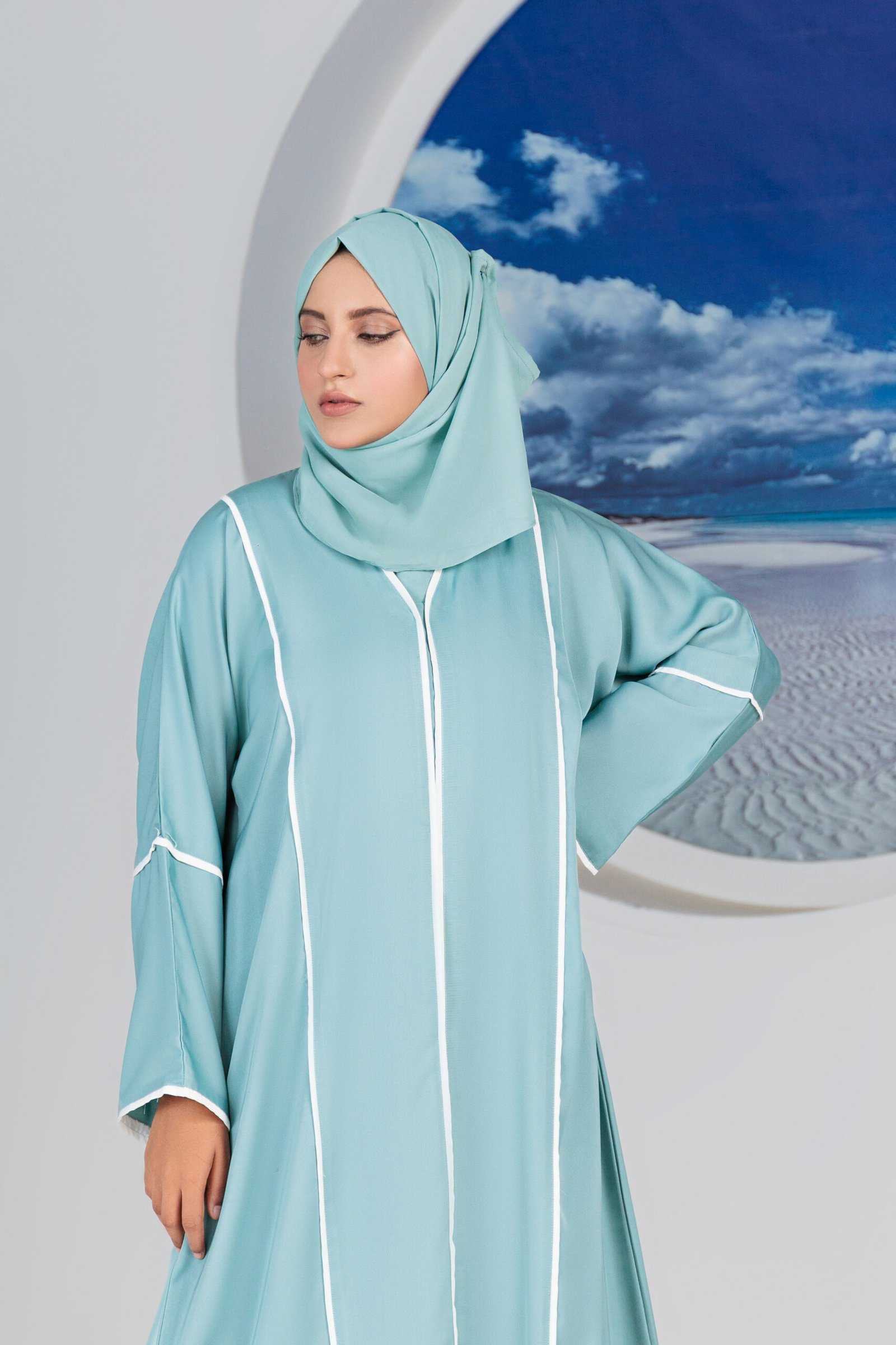 Woman in stylish blue abaya with scenic beach window view